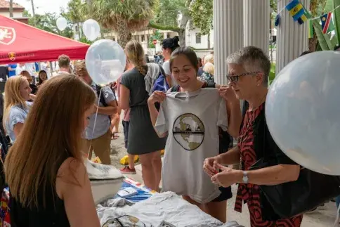 Student holds up promotional t-shirt at international center event. 