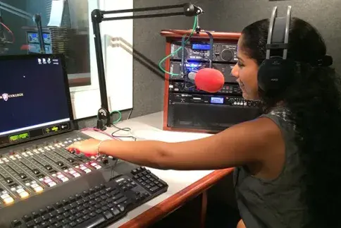 Female student speaking into a microphone at the Flagler College radio station.