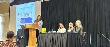 2024 Women in Sport panelists on stage with screen displaying the event name behind them.