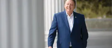 President Delaney posing between the columns of Markland House