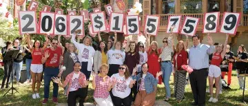 A group on the West Lawn. Individuals are holding up numbers. On group shows "2062" for the number of donors. Another group shows "$1,557,589" for the total donated.