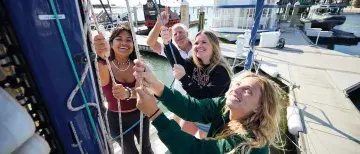 Students raising a sail on a boat.