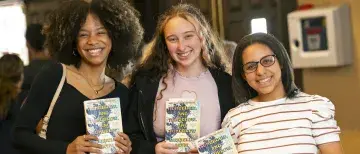 Three female students holding Zevin's novel smiling for group photo