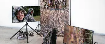 Bad Outdoorsmen: Katie HArgrave and Meredith Laura Lynn - image includes tv screens and backdrops with leaves