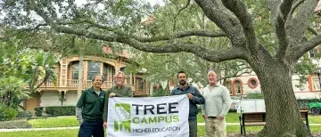Tree Campus Banner held by members of the advisory board on west lawn