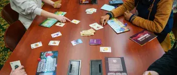 Aerial view of students playing board game at Library table