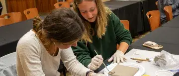 Two students working on a tile during a workshop on tile making