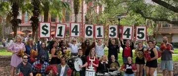Roar Raise Announcement - group of students and staff holding numbers showing the total dollars raised
