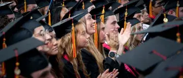 A group of graduates look up from the crowd
