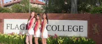Maria Montero stands with friends in front of a Flagler College sign