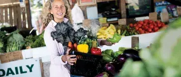 Dr. Carrie Grant holding a basket of vegetables at a market
