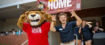 Joseph DelliSanti stands with Lewis The Lion while moving residents into Cedar Hall