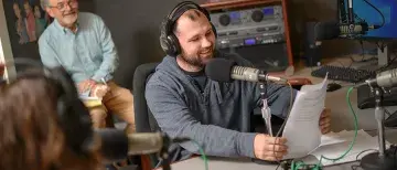 Visiting Filmmaker Jim Gilmore watches as a student records in the studio