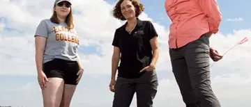 Student and professors standing around oysters on a river shore