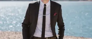Derek Boik standing on a beach with snow-capped mountains in the background