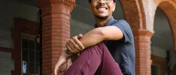 Flagler College student, Spencer Hooker, sitting on a wall near Ponce Hall