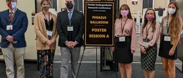 Flagler College students standing in front of the entrance to the Florida Undergraduate Research Conference