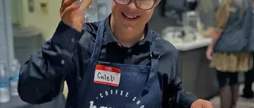 Happy Brew solo apron.jpeg Happy Brew employee with branded apron holding up a cup