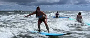 Student in Sam McMillan's Adventure Literature class surfing at Vilano Beach