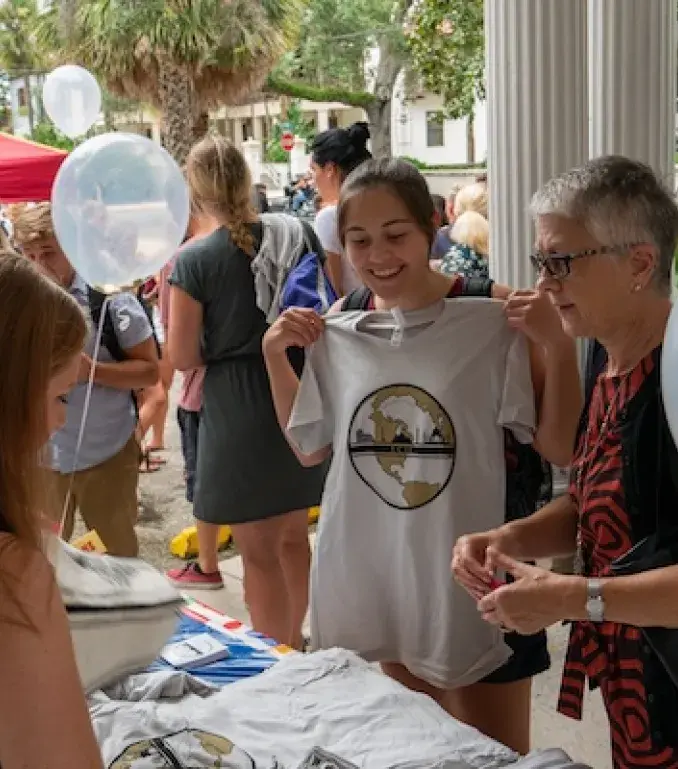 Student holds up promotional t-shirt at international center event. 