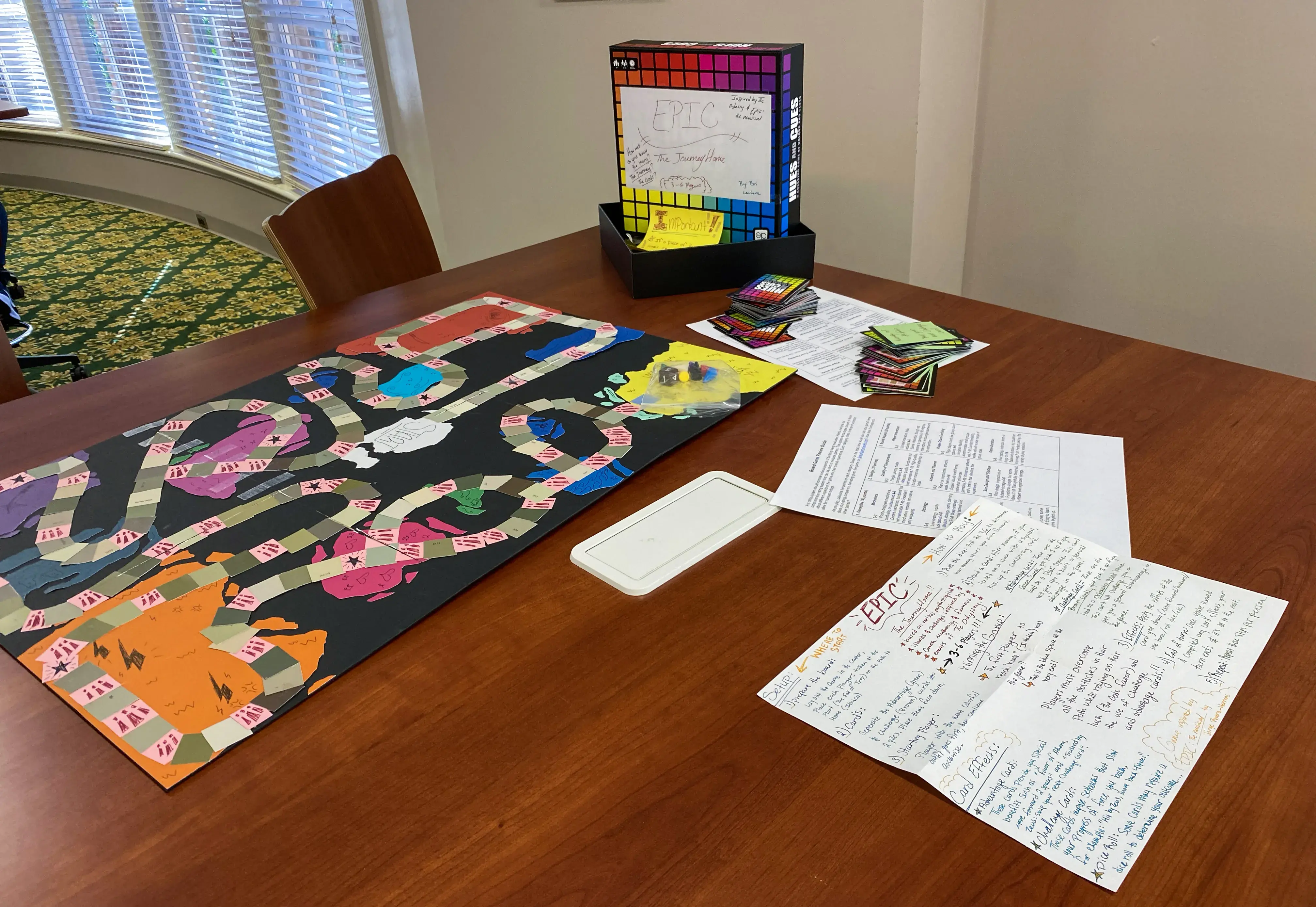 Photos of student-made game "Epic" on table with rule sheet nearby