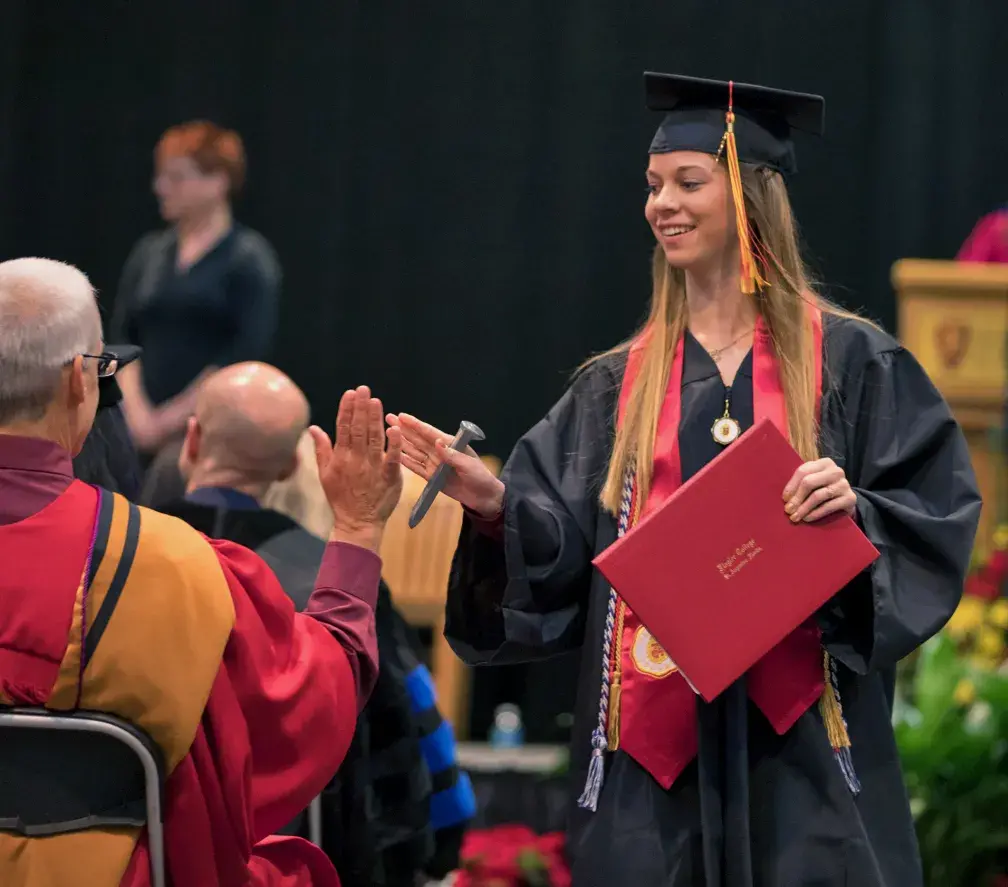 Student high-fiving at Commencement with spike in hand