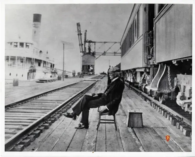 Henry Flagler sitting at bench of FEC Railway station (1908)