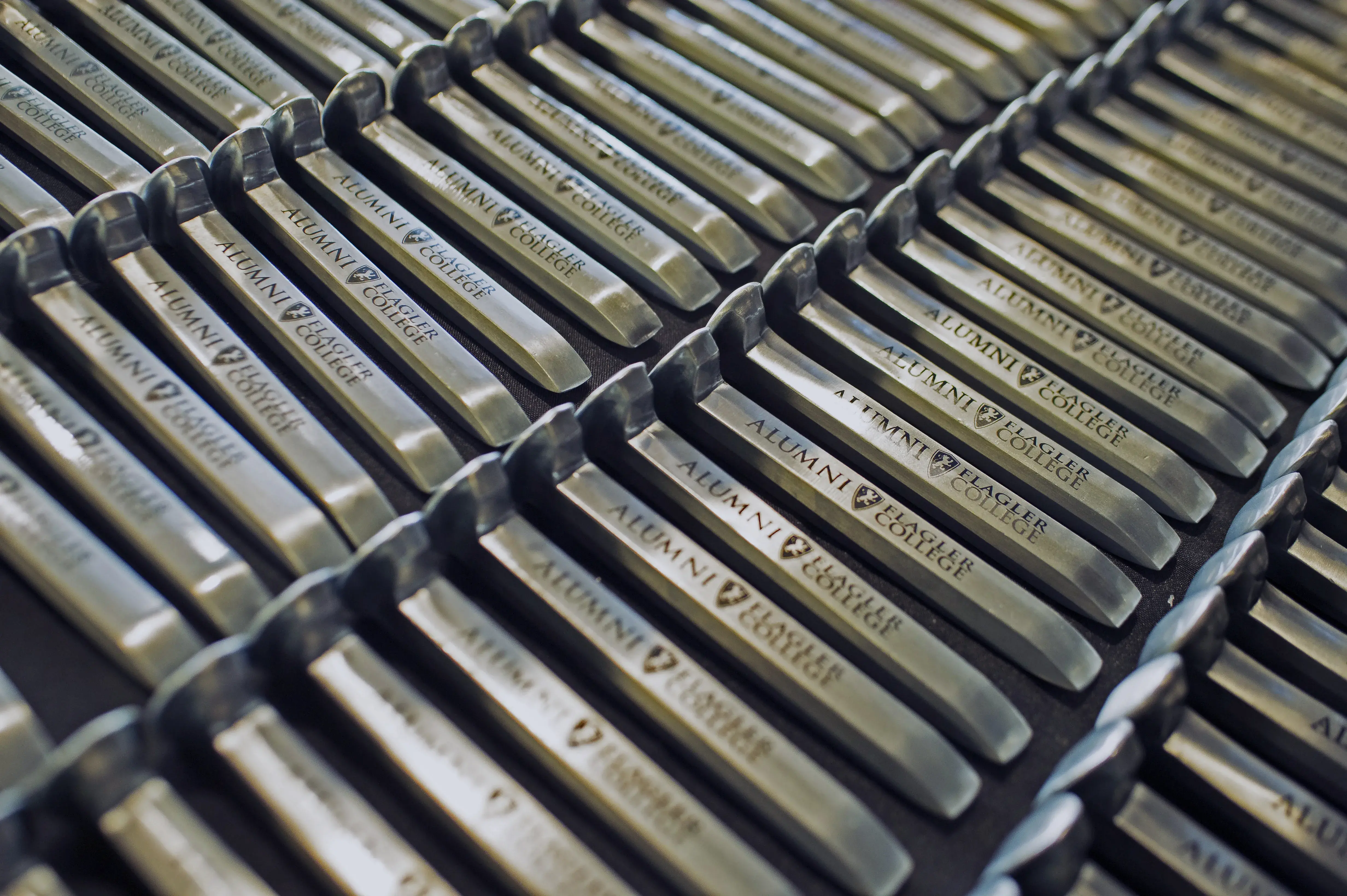 Close-up of table of silver railroad spikes at Commencement rbanded by the Alumni Association