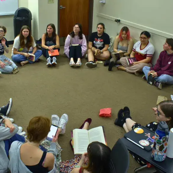 Read the Room club meeting - students sitting on the floor in a circle with books