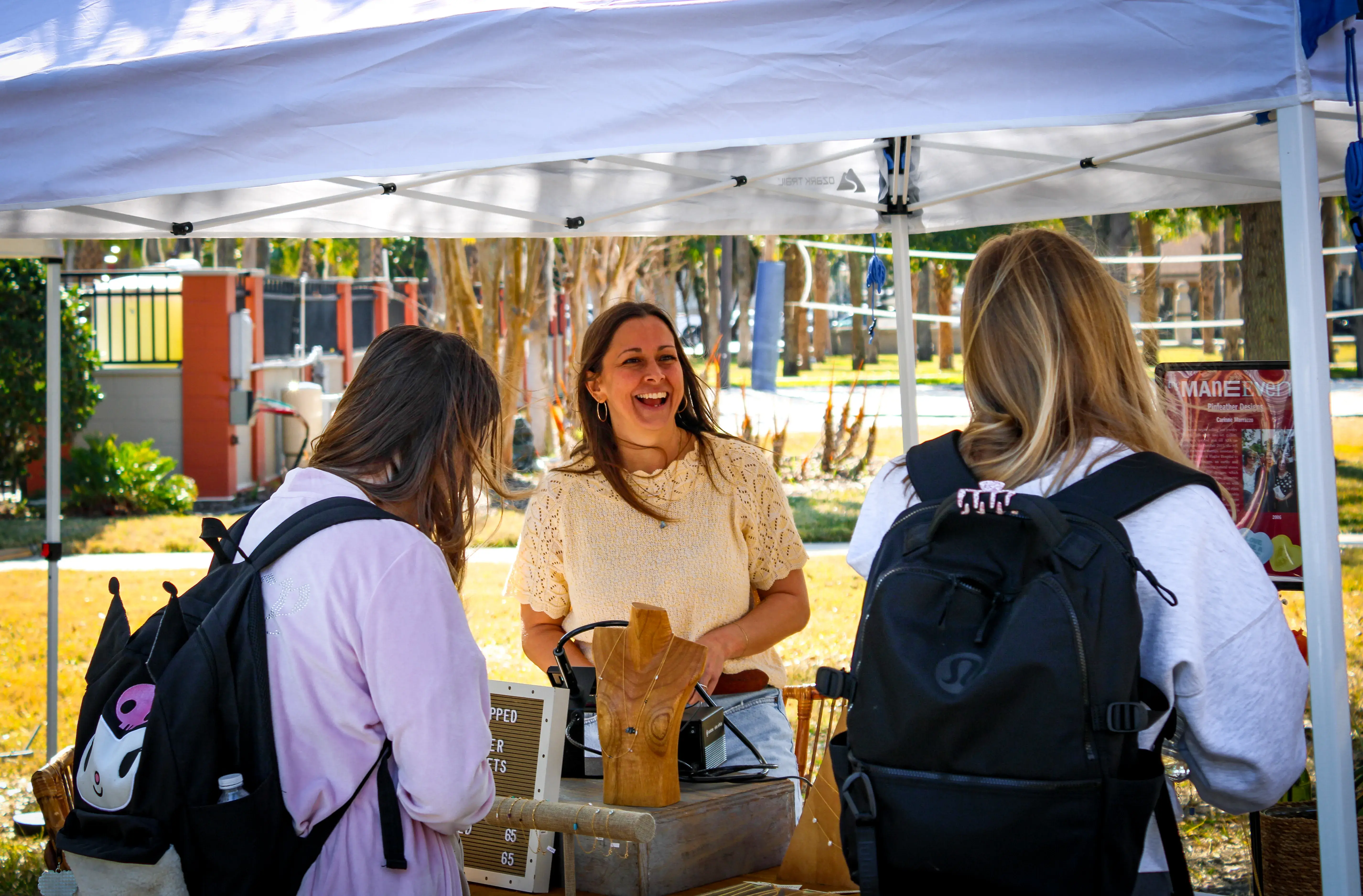 Alum and owner of Pinfeather Designs laughs with some students at her booth.