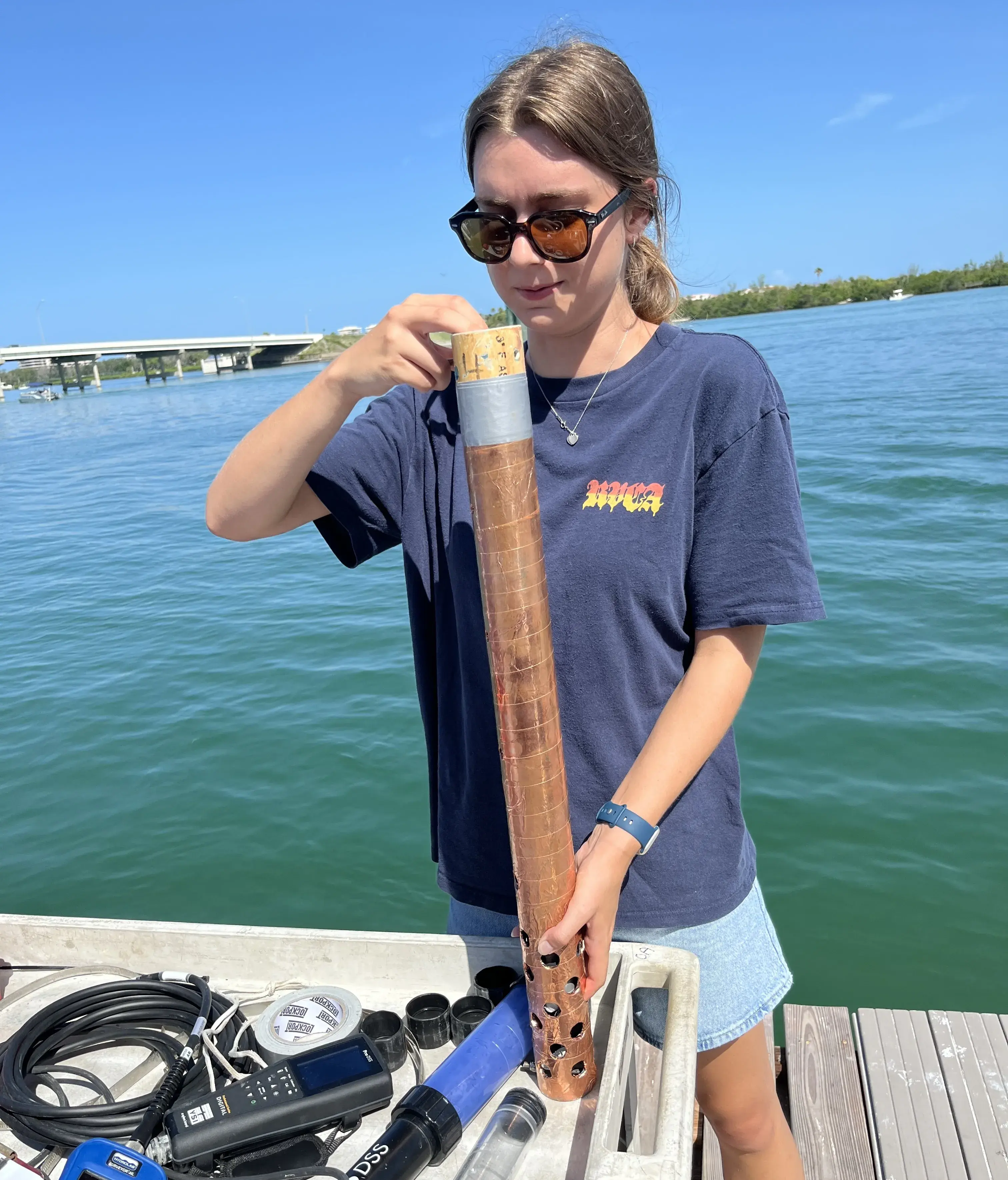 Zoe Kieffer on a dock collecting a water sample