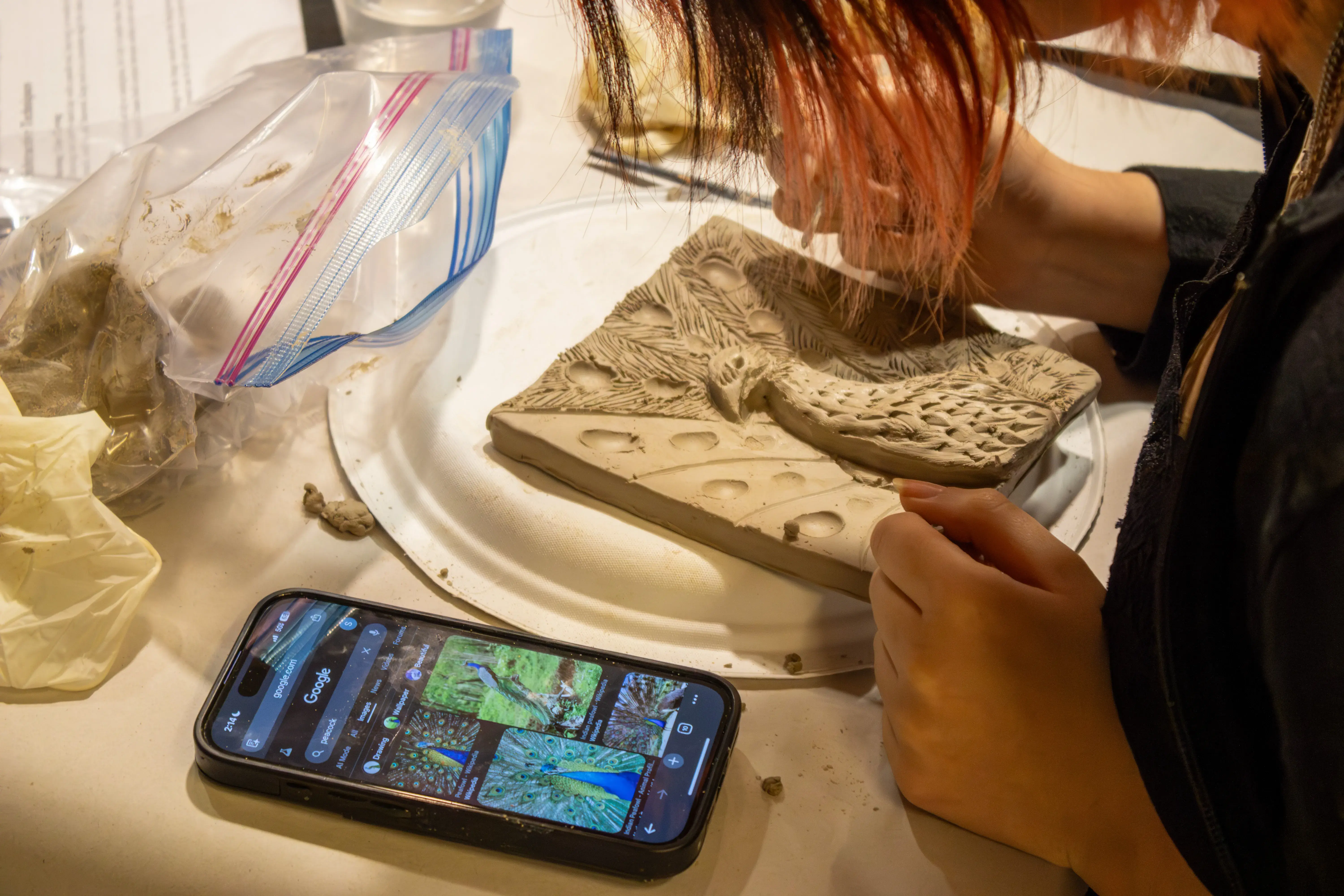 An over the shoulder view of a student working on a tile.