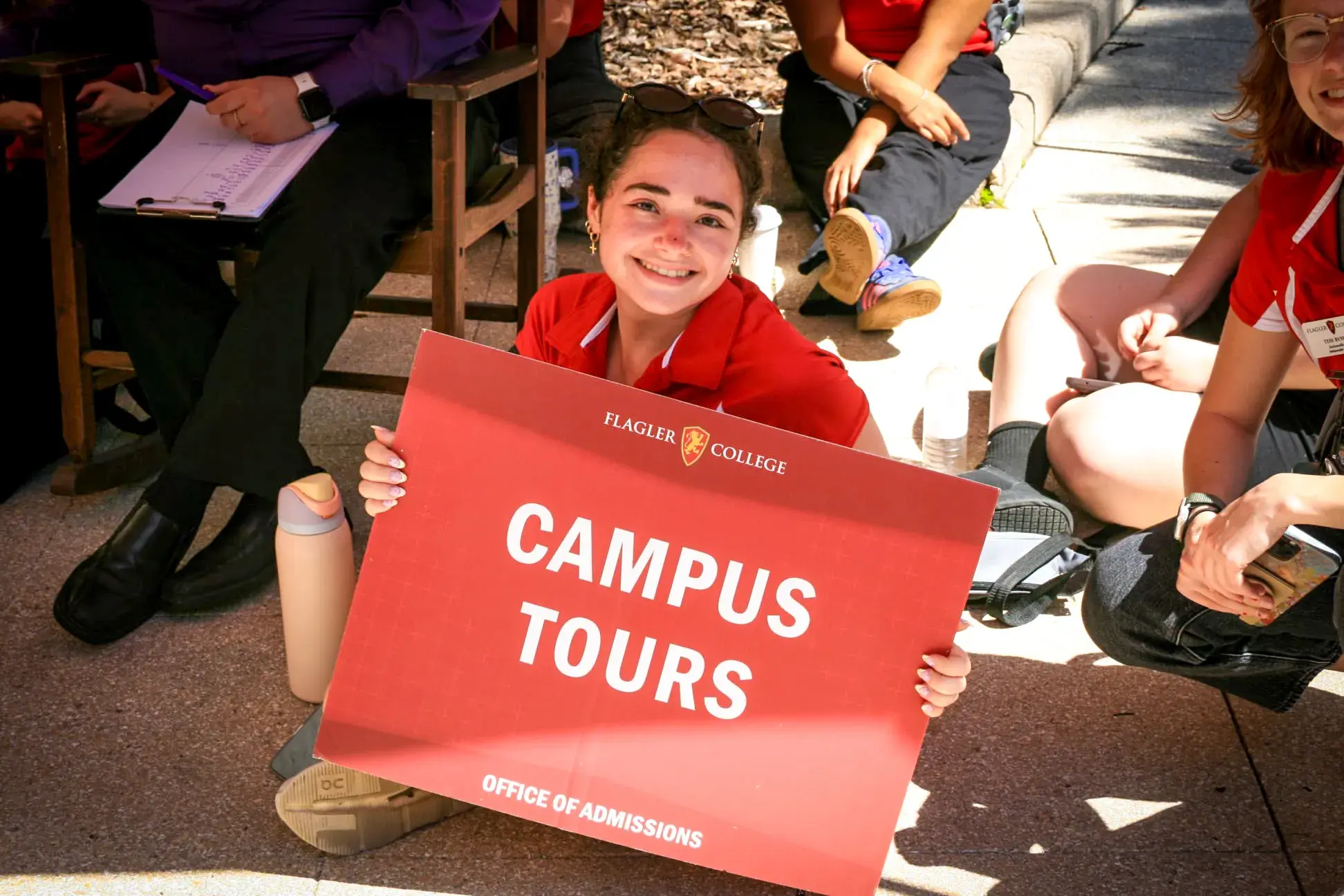 A student ambassador holding a sign that says "Student Tours" on it