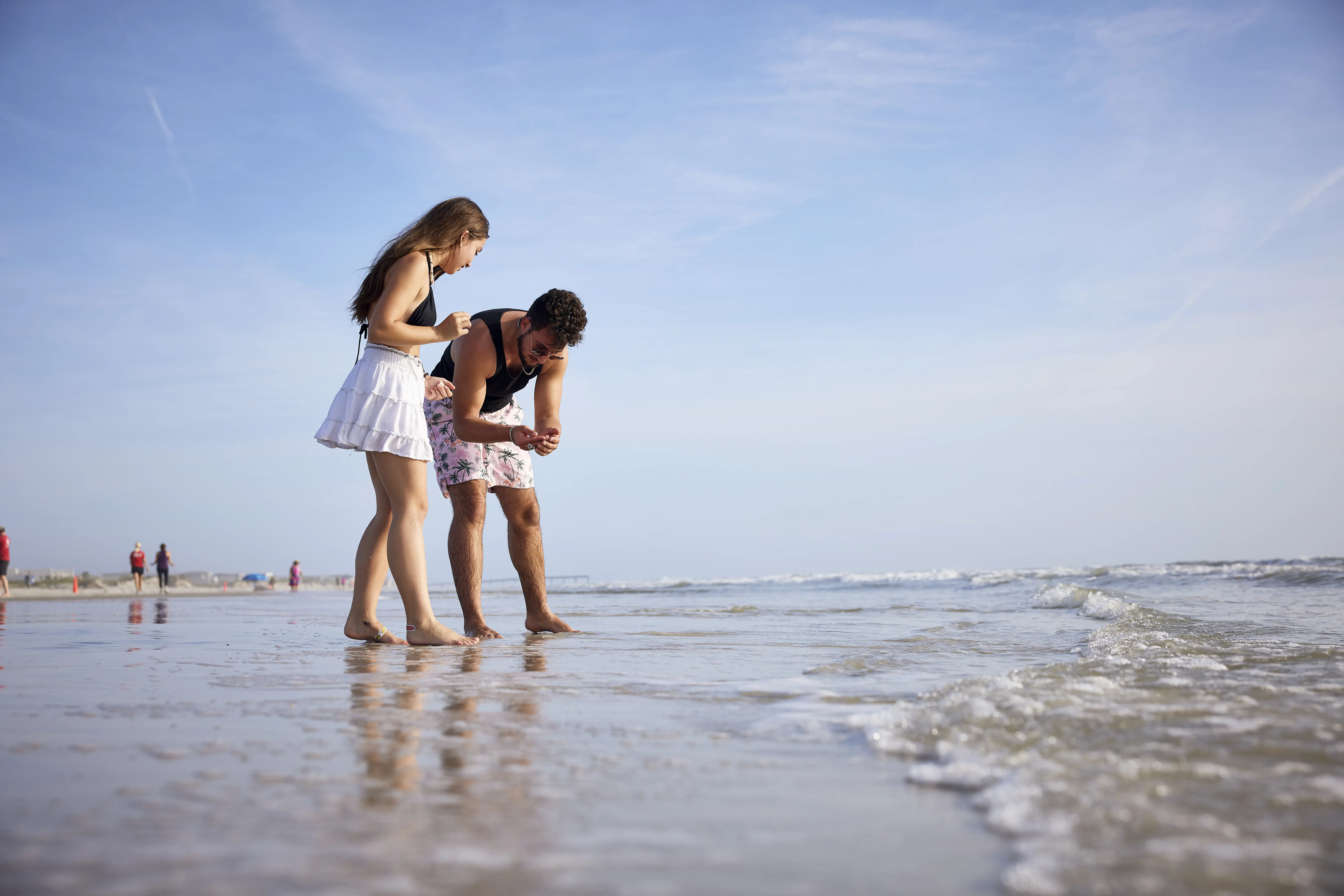 A view of two students inspecting a shell while on the beach