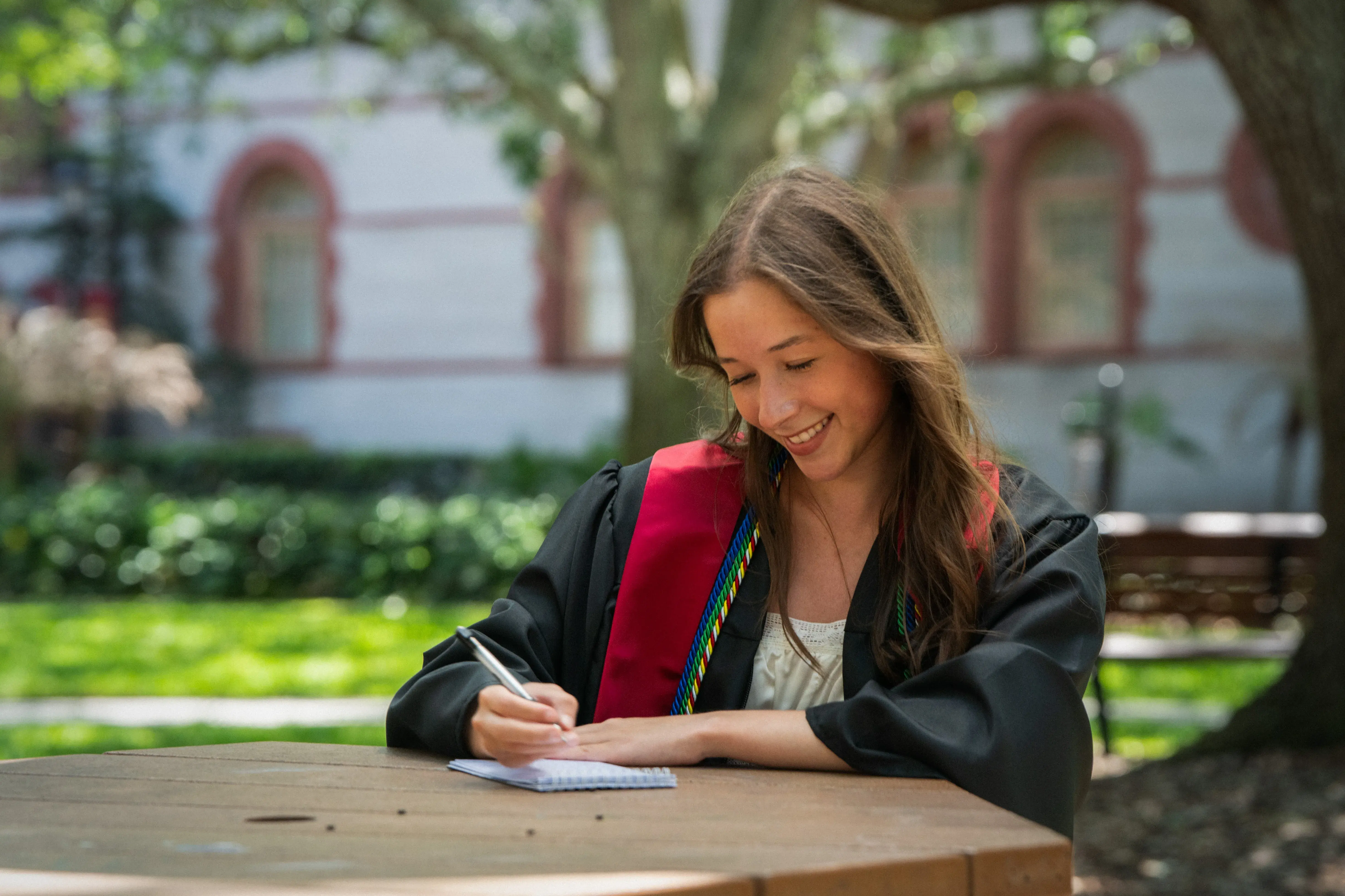 Sophia Cardona sits at a table and writes in a notepad
