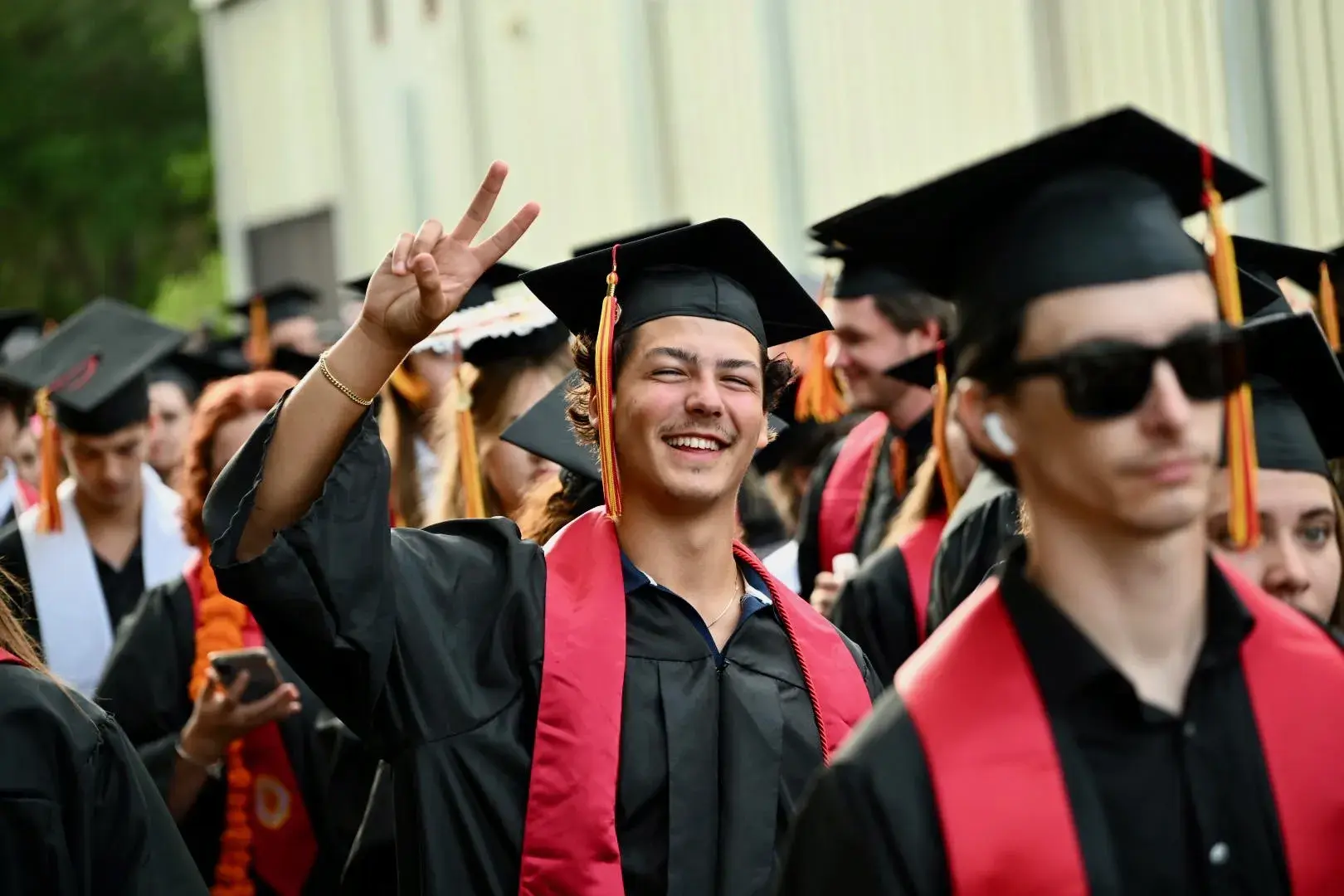 Graduate Randy Giglio gives the camera a peace sign at graduation