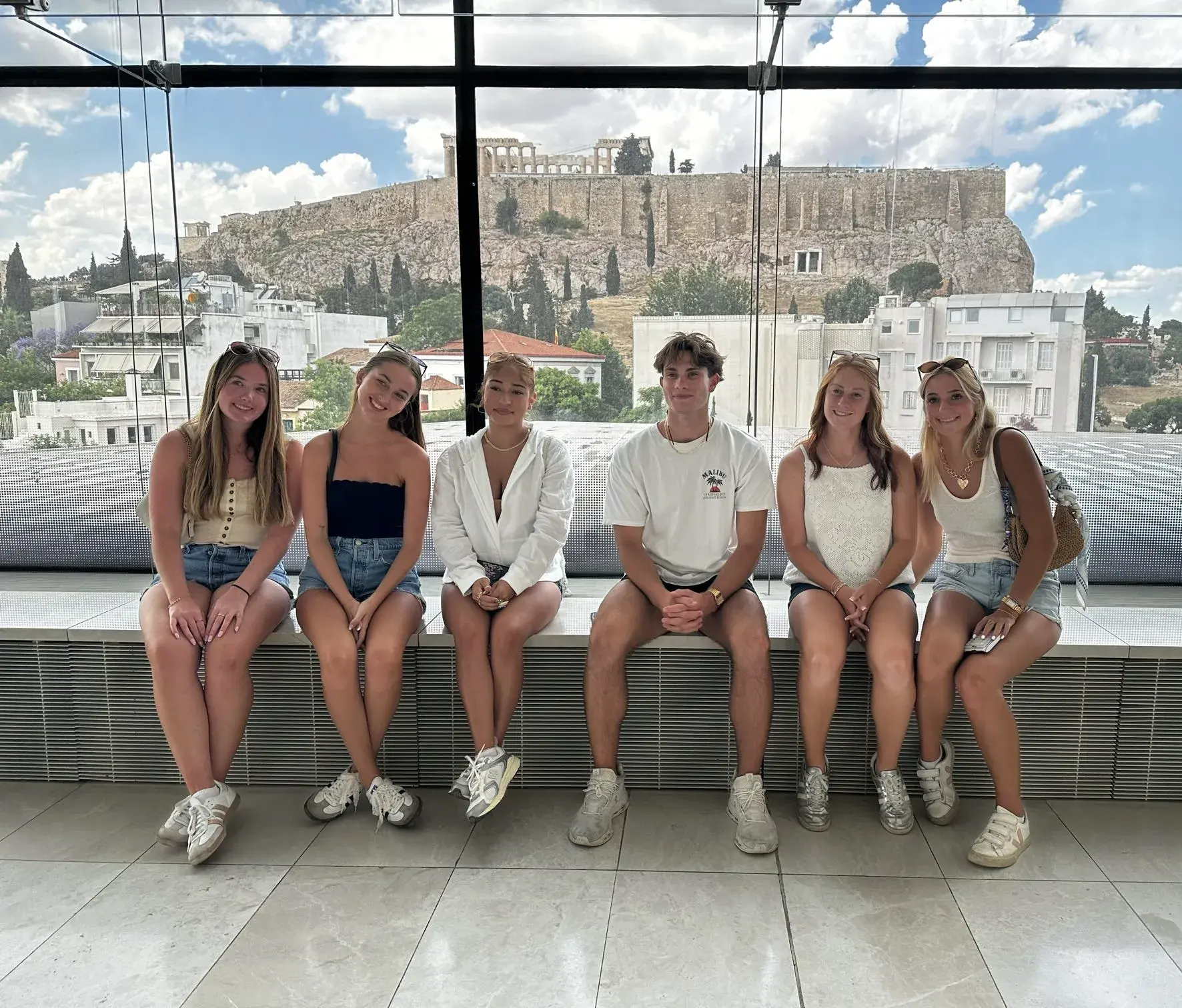 A group of students pose for a seated photo at the Acropolis Museum