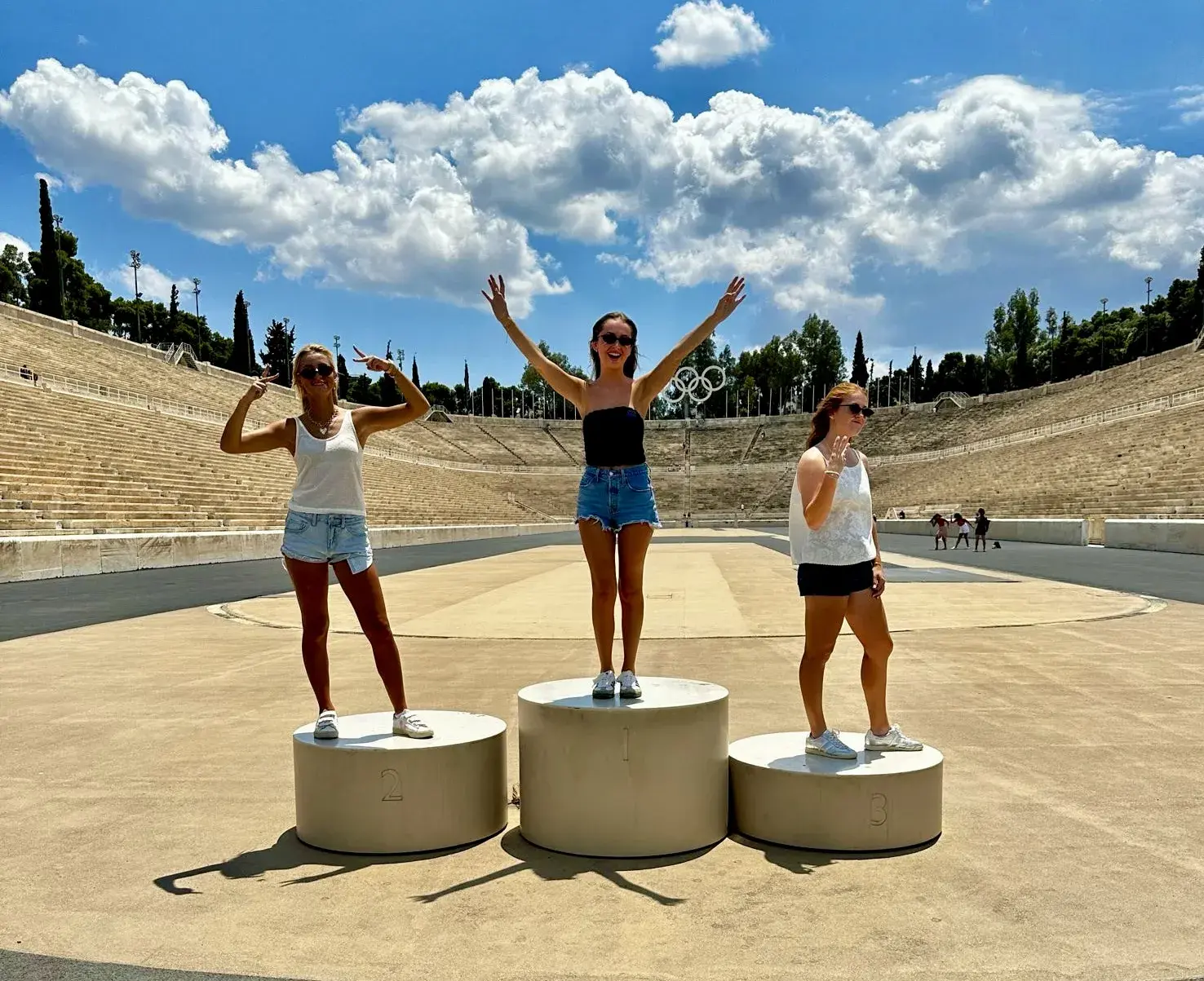 Three students pose on the olympic podium that still sits inside the Panathenaic Stadium