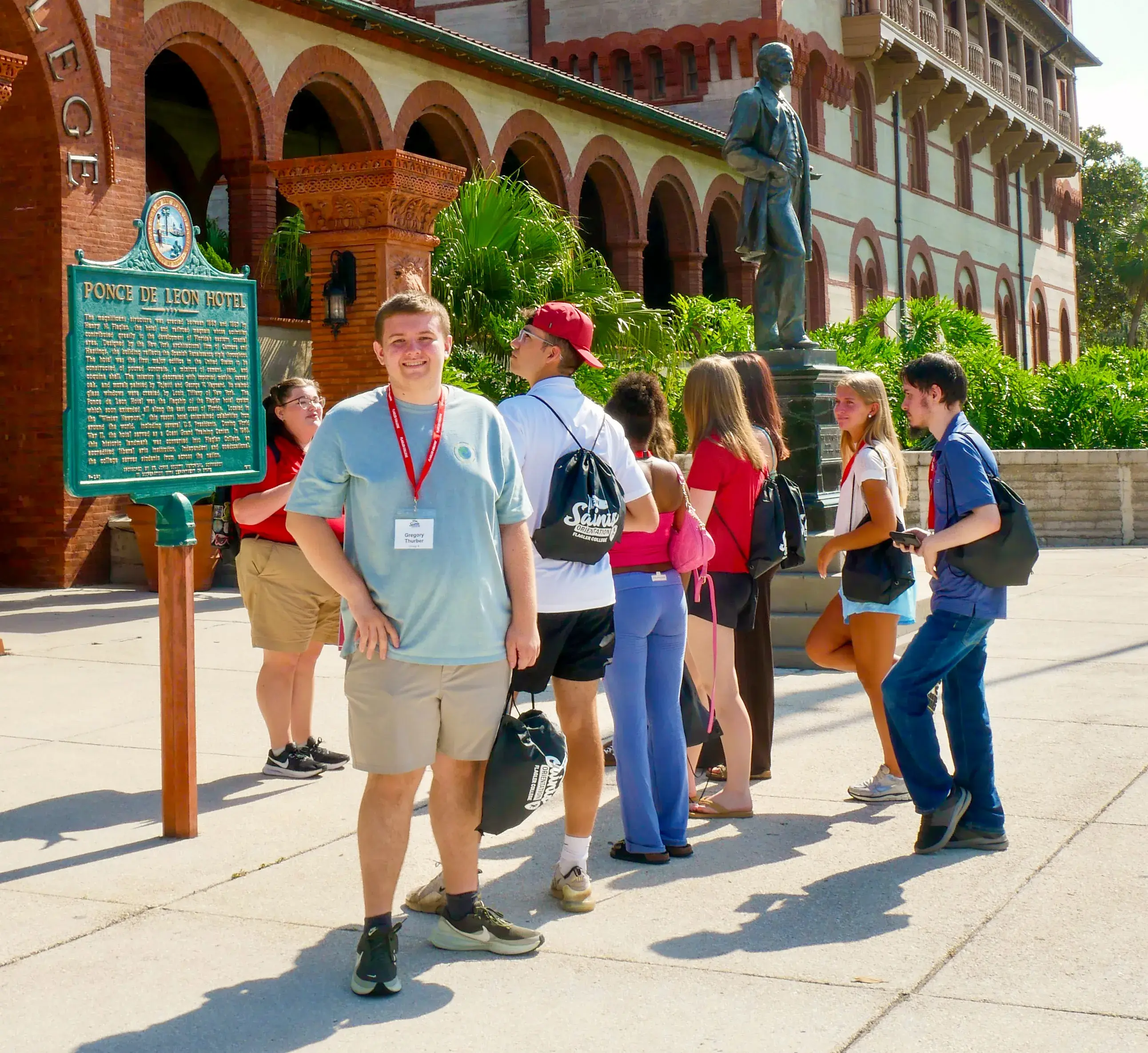 An orientation student smiles for the camera in front of a statue of Henry Flagler