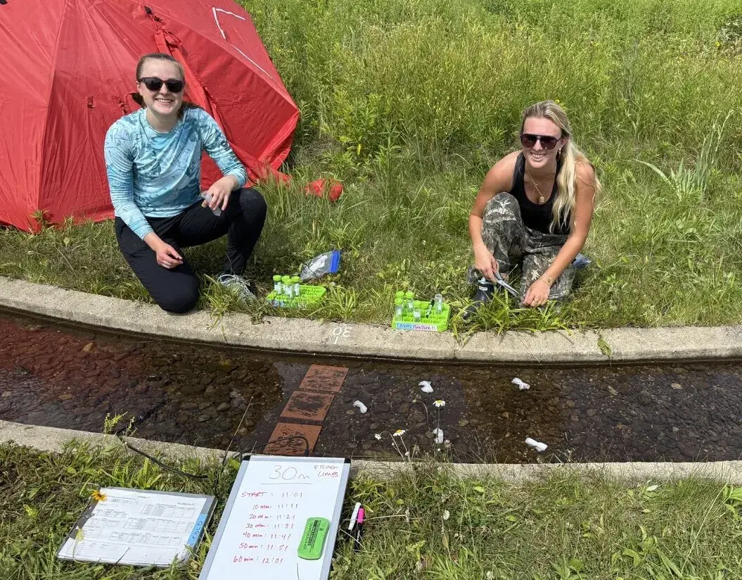 Barbara Tucker and a colleague collect samples from a stream
