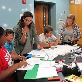 Flagler students and elementary school students gather together around table in science lab.